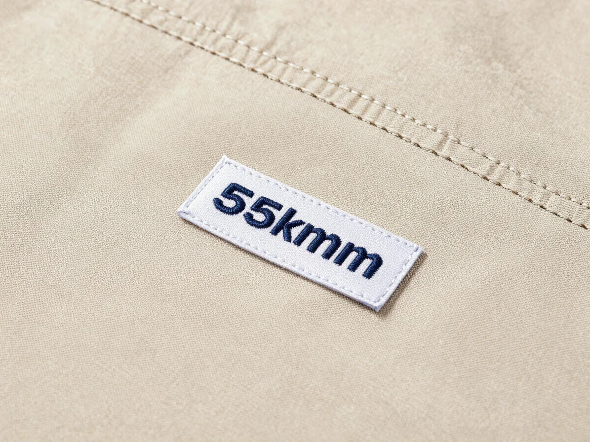 Macro studio photograph of an embroidered logo and woven brand la
